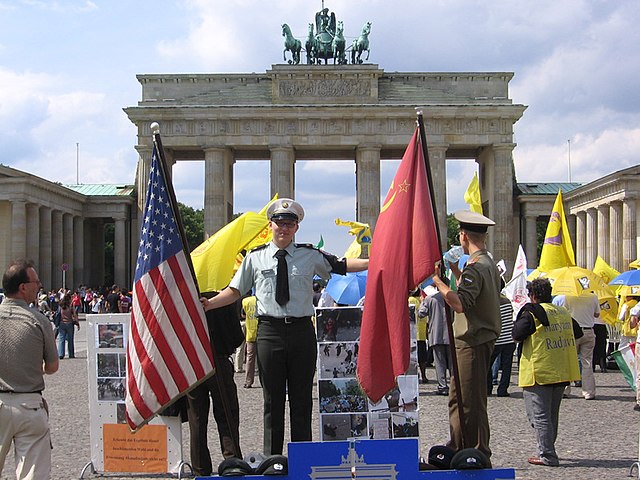 <u>Query</u>: An officer hoisting international flags in front of a neoclassical monument of a gate<br>
      <u>Named Entity</u>: Brandenburg Gate